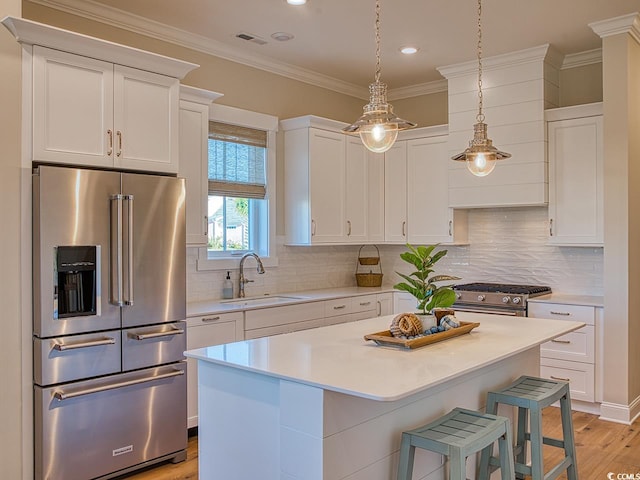 kitchen with decorative backsplash, a center island, high end appliances, light hardwood / wood-style flooring, and sink