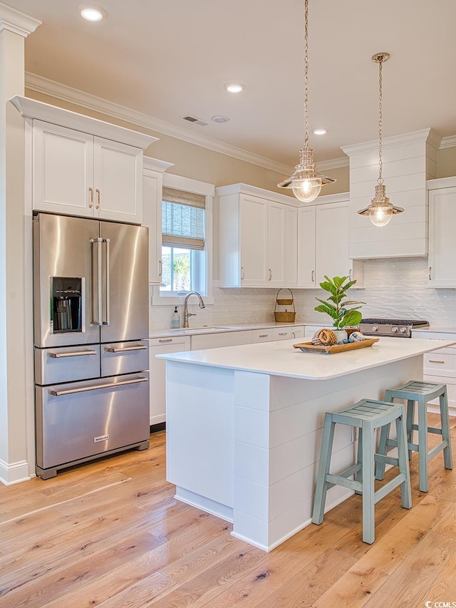 kitchen featuring light wood-type flooring, a kitchen island, premium appliances, and backsplash