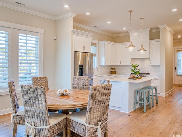 dining space with light wood finished floors, visible vents, crown molding, and baseboards