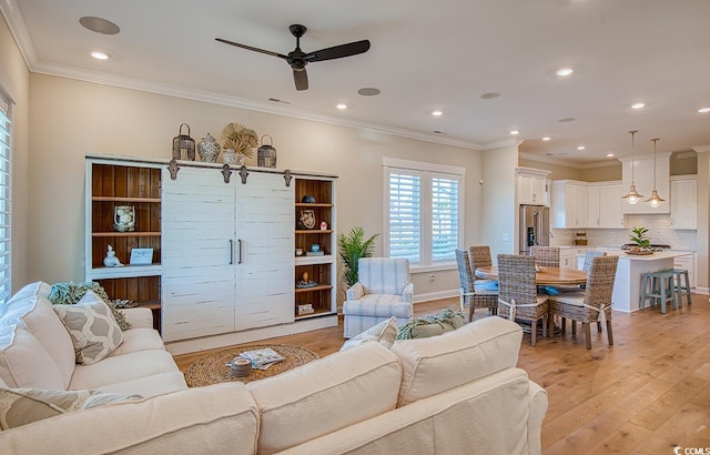 living room featuring ceiling fan, ornamental molding, and light hardwood / wood-style floors