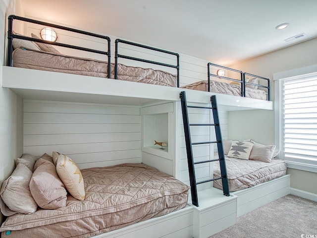 carpeted bedroom with visible vents and wood walls