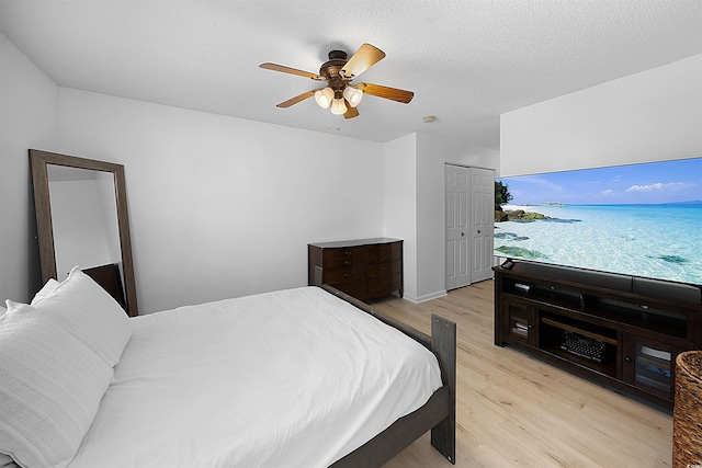 bedroom with light wood-type flooring, a textured ceiling, a closet, and ceiling fan