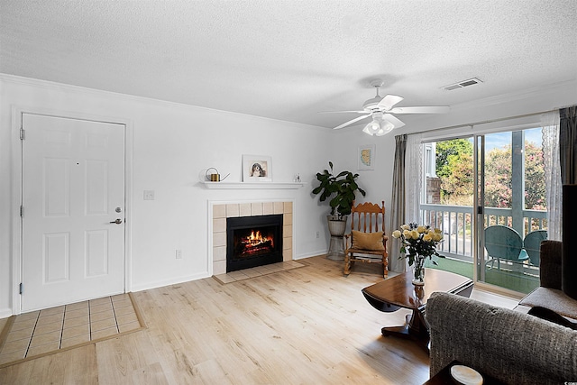 living room featuring ornamental molding, a textured ceiling, and a tiled fireplace