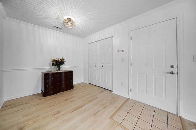 foyer with a textured ceiling, ornamental molding, and light wood-type flooring