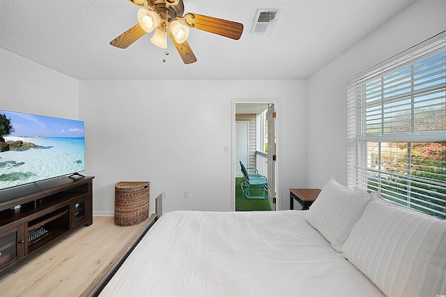 bedroom featuring light wood-type flooring, ceiling fan, and a textured ceiling