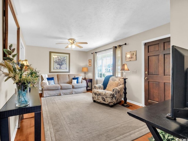 living room with hardwood / wood-style flooring, a textured ceiling, and ceiling fan