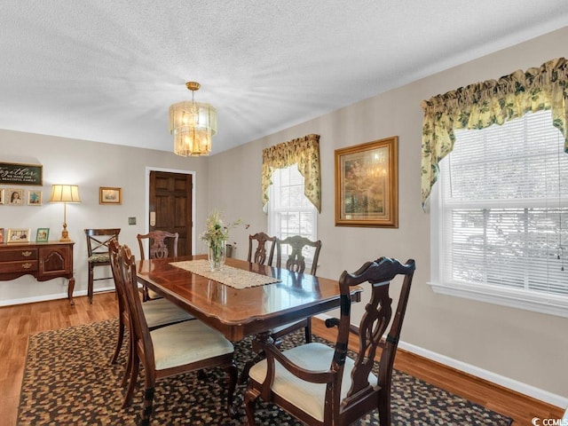 dining room with an inviting chandelier, wood-type flooring, and a textured ceiling