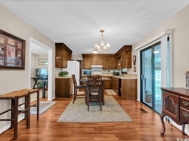 kitchen featuring an inviting chandelier, backsplash, light hardwood / wood-style floors, and decorative light fixtures