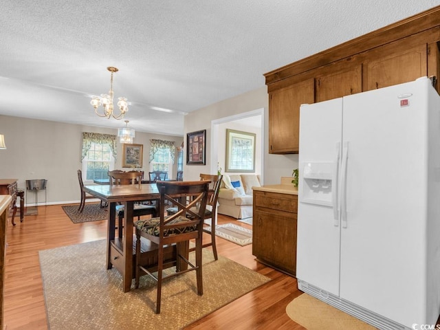 dining space with a chandelier, a textured ceiling, and light hardwood / wood-style flooring