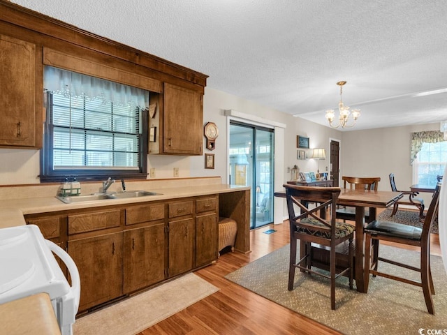 kitchen with sink, pendant lighting, a textured ceiling, and light hardwood / wood-style flooring