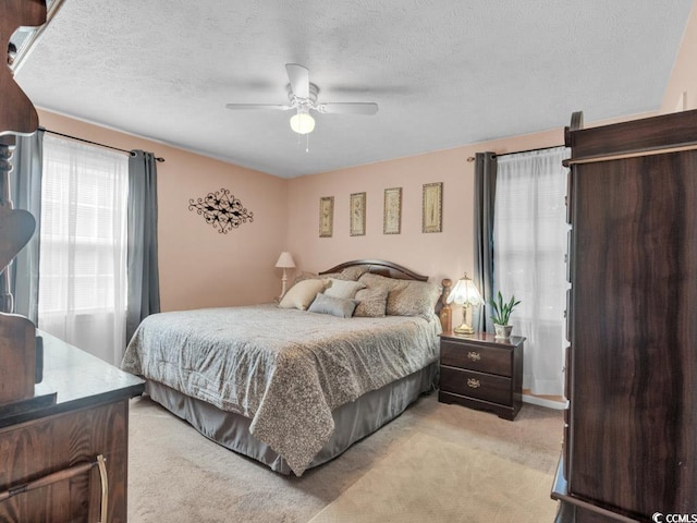 bedroom featuring ceiling fan, light colored carpet, and multiple windows