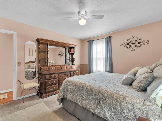 bedroom with ceiling fan, carpet floors, and a textured ceiling