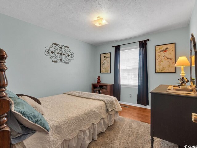 bedroom with light hardwood / wood-style flooring and a textured ceiling