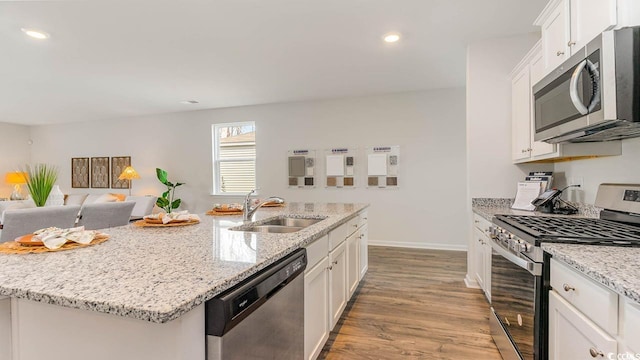 kitchen with a center island with sink, sink, light wood-type flooring, white cabinetry, and stainless steel appliances