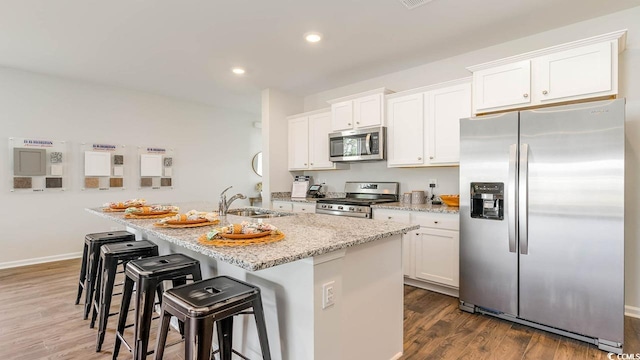 kitchen with a kitchen island with sink, sink, dark hardwood / wood-style flooring, white cabinetry, and stainless steel appliances