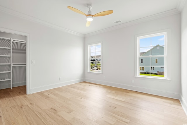 empty room featuring ornamental molding, light wood-type flooring, visible vents, and baseboards