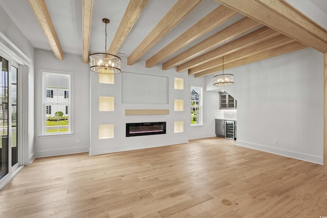 unfurnished living room featuring wine cooler, a glass covered fireplace, light wood-style flooring, and an inviting chandelier