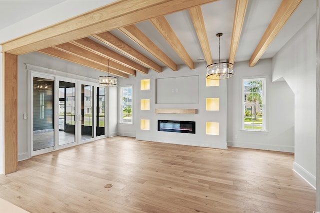 unfurnished living room with light wood-style floors, a glass covered fireplace, beam ceiling, and an inviting chandelier