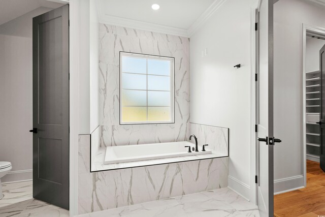 bathroom with plenty of natural light, tiled tub, wood-type flooring, and toilet