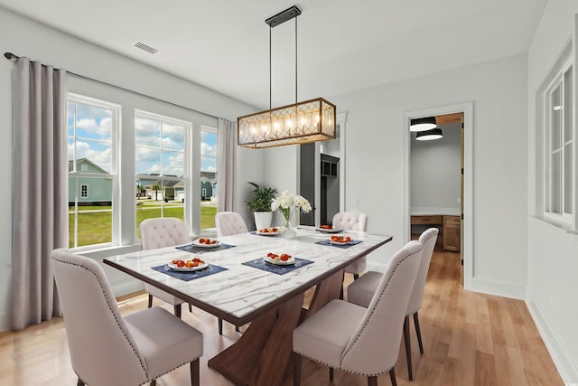 dining room featuring light wood-type flooring, visible vents, and baseboards