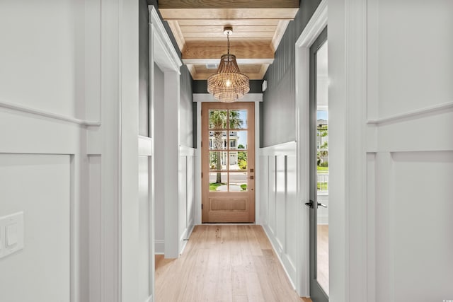 doorway with a chandelier, light wood-type flooring, and wooden ceiling