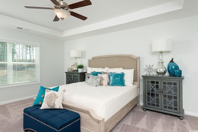 bedroom with carpet floors, a tray ceiling, and ceiling fan