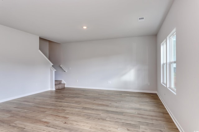 spare room with baseboards, stairs, and light wood finished floors