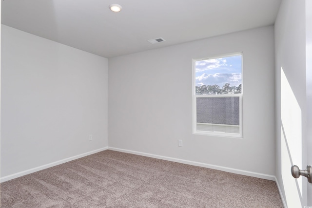 carpeted spare room featuring baseboards and visible vents