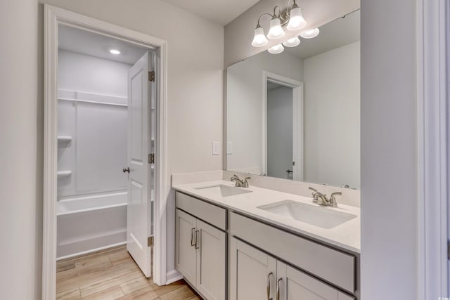 bathroom featuring double vanity, wood finished floors, a sink, and a tub to relax in