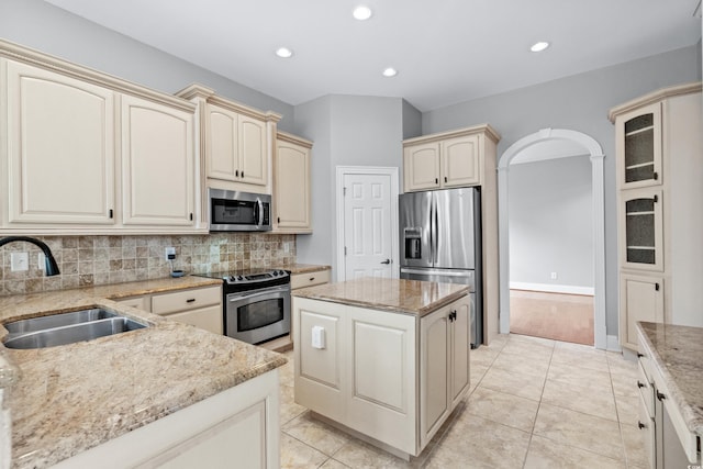 kitchen featuring sink, tasteful backsplash, cream cabinetry, a kitchen island, and stainless steel appliances