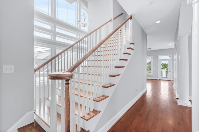 stairway featuring hardwood / wood-style flooring and decorative columns