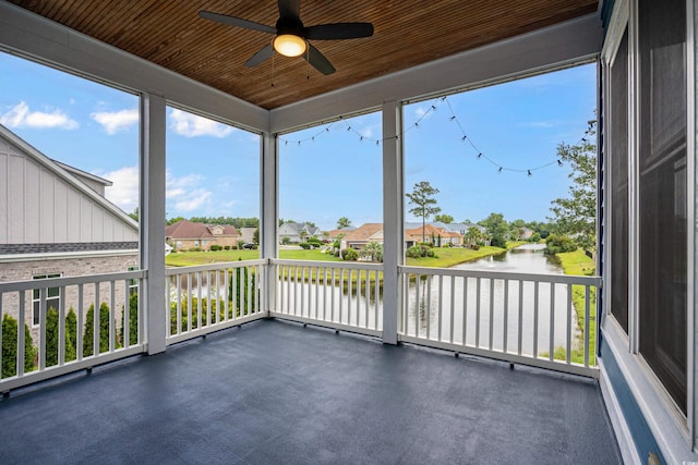 unfurnished sunroom with ceiling fan, a water view, and wooden ceiling