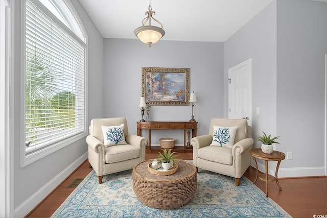 living area featuring visible vents, a wealth of natural light, wood finished floors, and baseboards