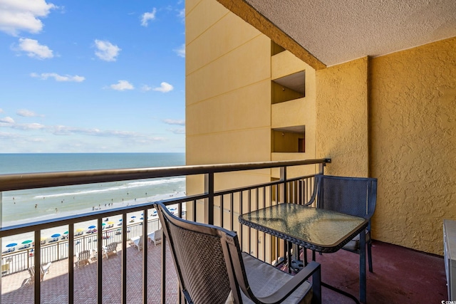 balcony with a water view and a view of the beach