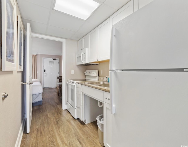 kitchen with a drop ceiling, white appliances, light hardwood / wood-style flooring, sink, and white cabinets