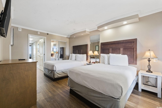 bedroom with wood-type flooring, ornamental molding, and a closet