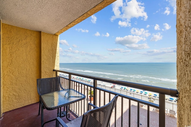 balcony featuring a view of the beach and a water view