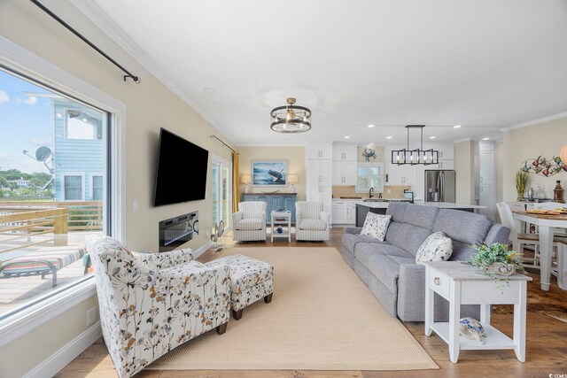 living room with ornamental molding, a notable chandelier, and light hardwood / wood-style flooring