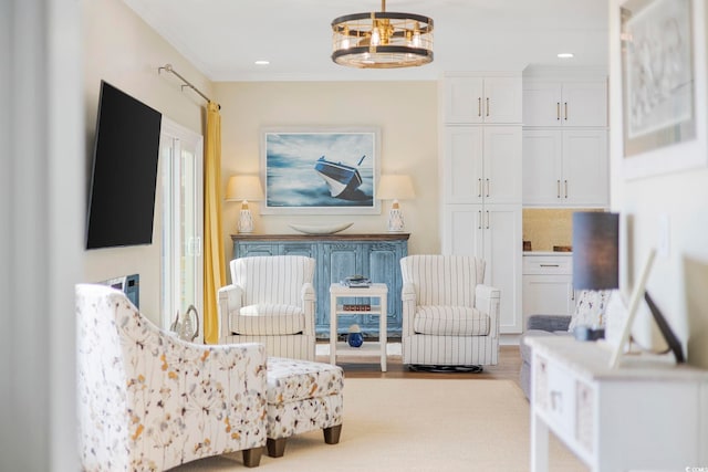 living area featuring an inviting chandelier, light hardwood / wood-style flooring, and ornamental molding