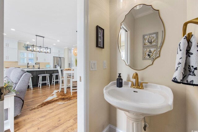 bathroom with crown molding, sink, hardwood / wood-style floors, and a notable chandelier