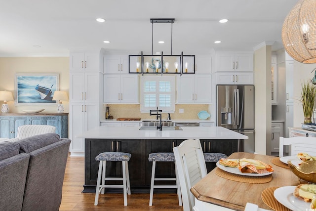 kitchen with white cabinetry, decorative light fixtures, a kitchen island with sink, and stainless steel fridge with ice dispenser