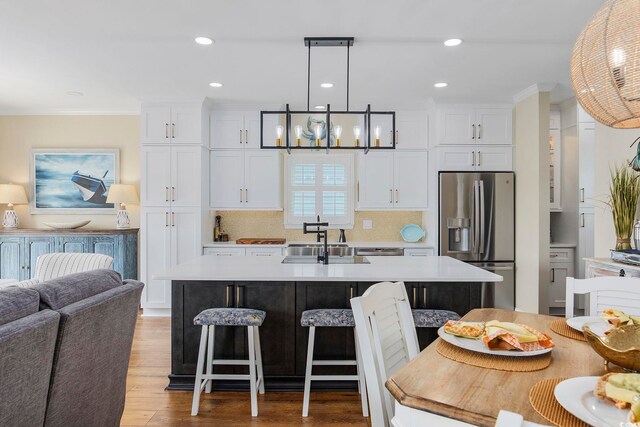 4524 Landing Rd, Little River, SC 29566 - kitchen featuring stainless steel fridge, a kitchen island with sink, light countertops, a breakfast bar area, and white cabinetry