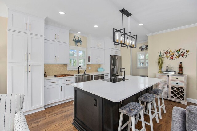 kitchen featuring an island with sink, white cabinets, hanging light fixtures, hardwood / wood-style flooring, and stainless steel appliances