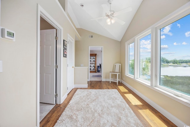 hallway featuring a water view, a healthy amount of sunlight, lofted ceiling, and light hardwood / wood-style flooring