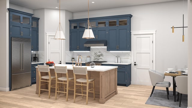 kitchen featuring blue cabinets, an island with sink, backsplash, stainless steel built in refrigerator, and light wood-type flooring