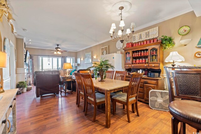 dining room featuring ceiling fan with notable chandelier, wood-type flooring, and crown molding