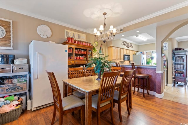 dining space with a notable chandelier, light hardwood / wood-style floors, and ornamental molding