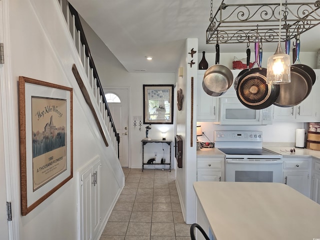 kitchen with white cabinetry, pendant lighting, light tile patterned flooring, and white appliances