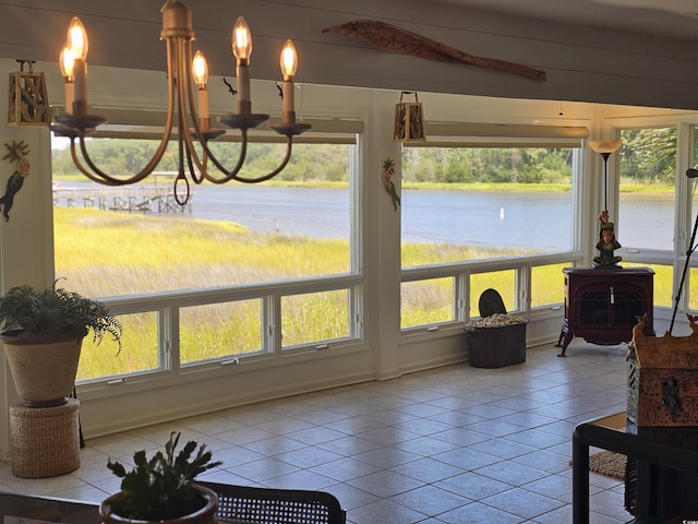 sunroom / solarium with a water view, an inviting chandelier, and a wood stove