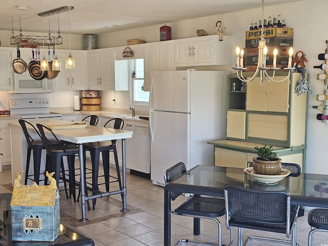 kitchen featuring light tile patterned flooring, a breakfast bar area, white cabinetry, decorative light fixtures, and white appliances